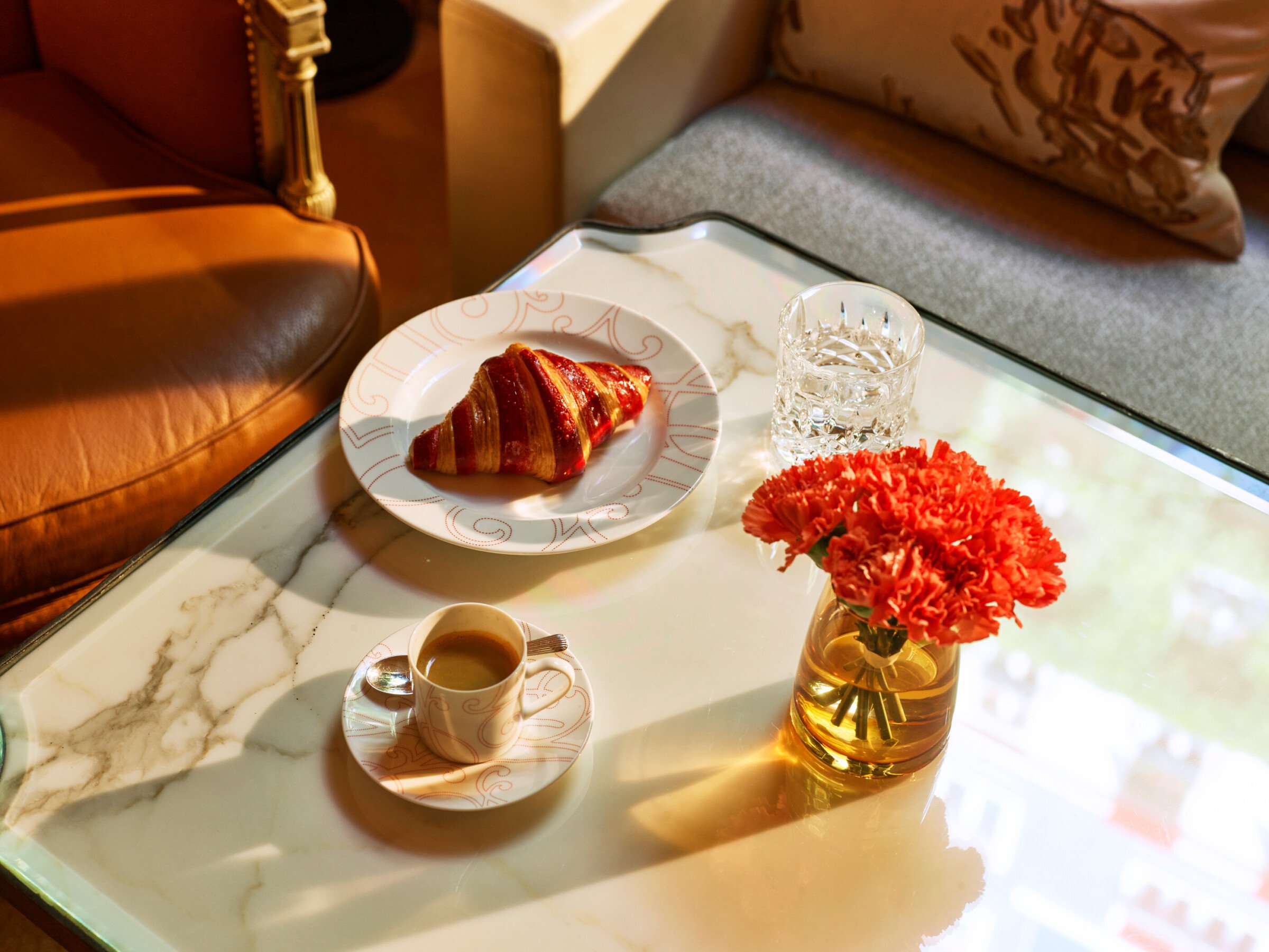 近距离拍摄la galerie的白色大理石餐桌，一杯咖啡，盘子里有一个羊角面包和一盆红色天竺葵，酒店广场Athénée，巴黎