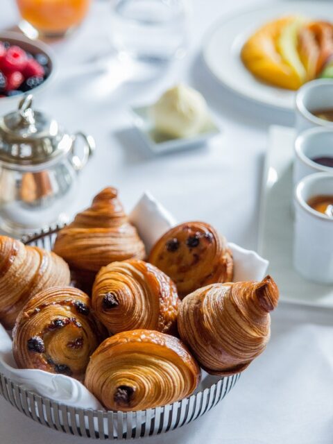 图片de pains aux巧克力和羊角包在corbeille, posés sur la table au sein hôtel Le Meurice à巴黎。