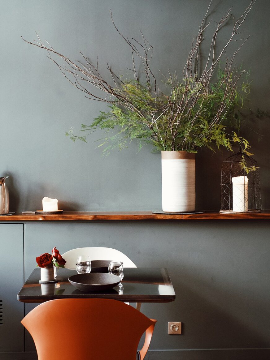 一张桌子后面的架子上放着一株茂密的植物