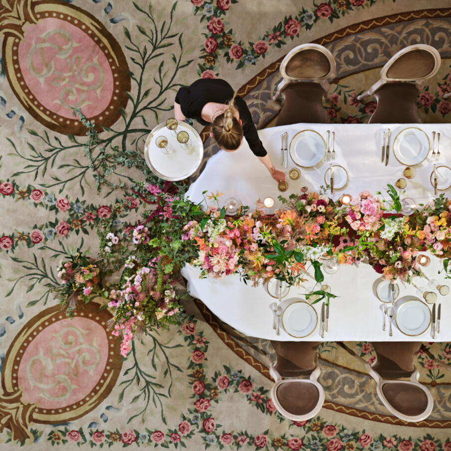 在Le Salon Pompadour的私人晚餐，从顶部捕捉到长长的插花和服务员在Le Meurice, Paris - Dorchester Collection。bob手机网页版官网