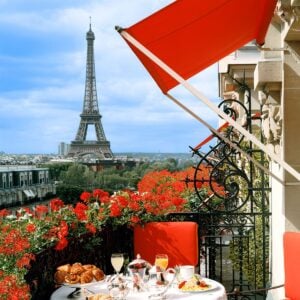 这张照片拍摄的是埃菲尔铁塔和一份在广场阳台上的早餐，上面有红色天竺葵