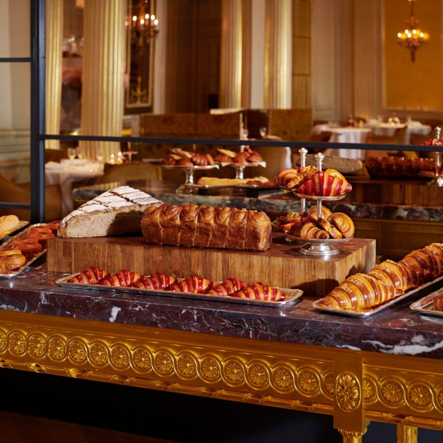 金色和大理石的桌子在Hôtel广场Athénée，巴黎与我们的新鲜烘焙糕点的选择，背面的镜子反射。