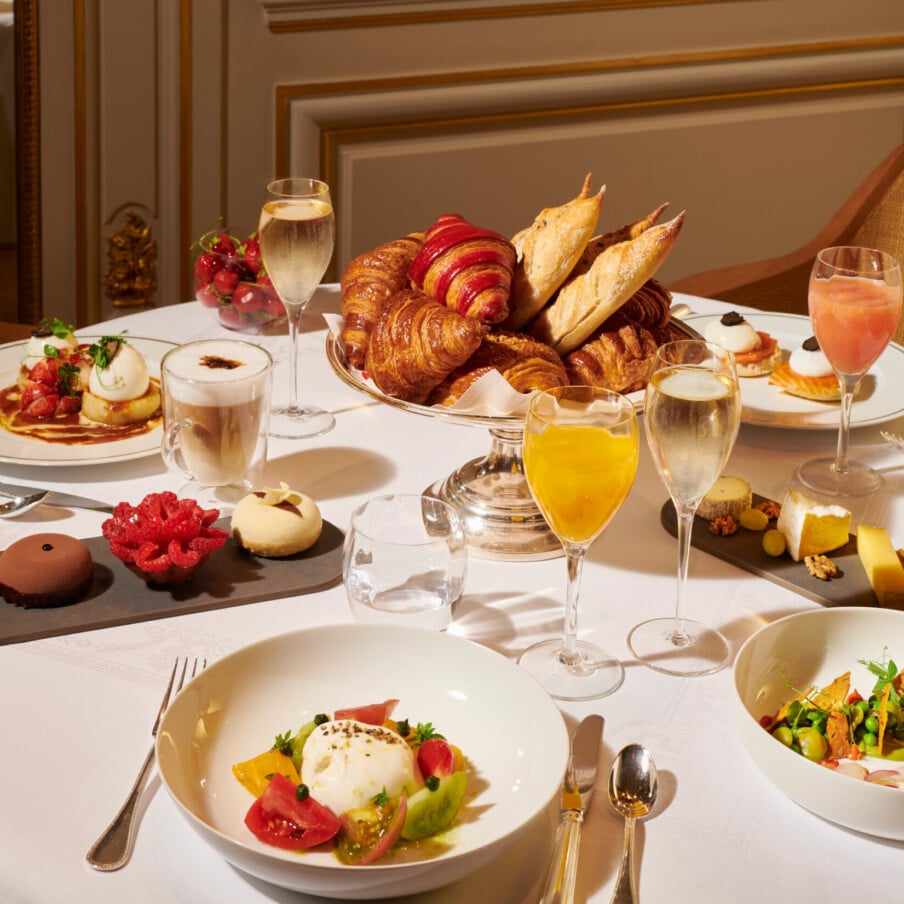 早午餐桌上有4个盘子，有鱼、西红柿、鸡蛋和鲑鱼，旁边还有糕点、香槟和果汁。