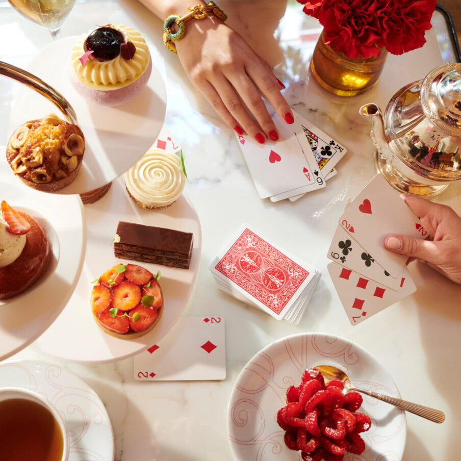 在巴黎广场酒店Athénée，两名女子在La Galerie喝茶时打牌，旁边放着各式各样的Angelo Musa糕点和香槟